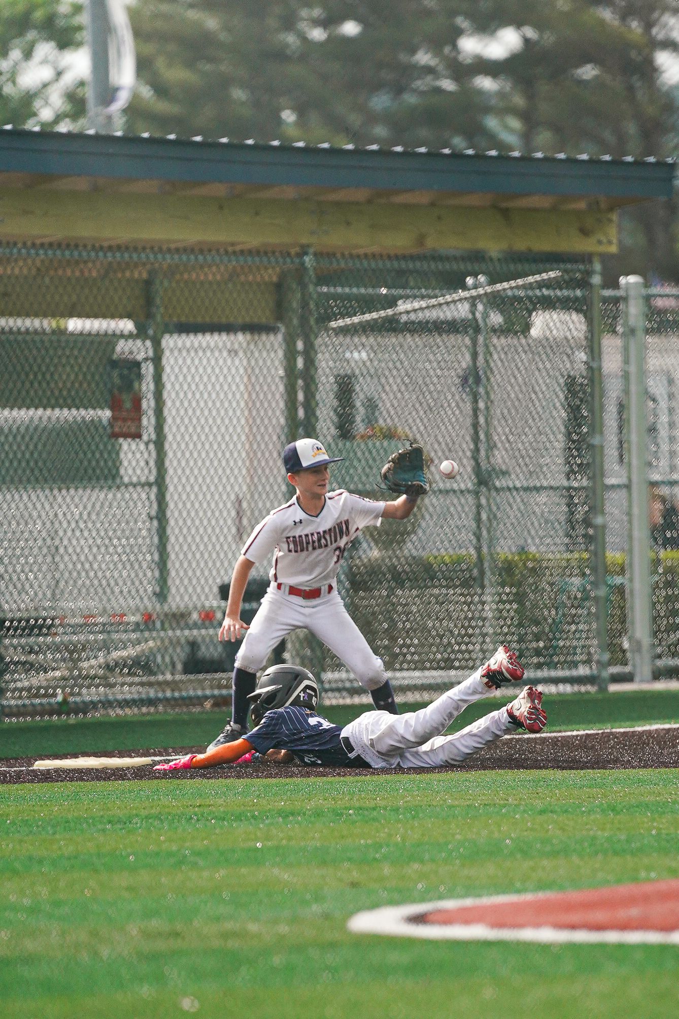 Baseball players sliding and diving for catch on grass field during game.