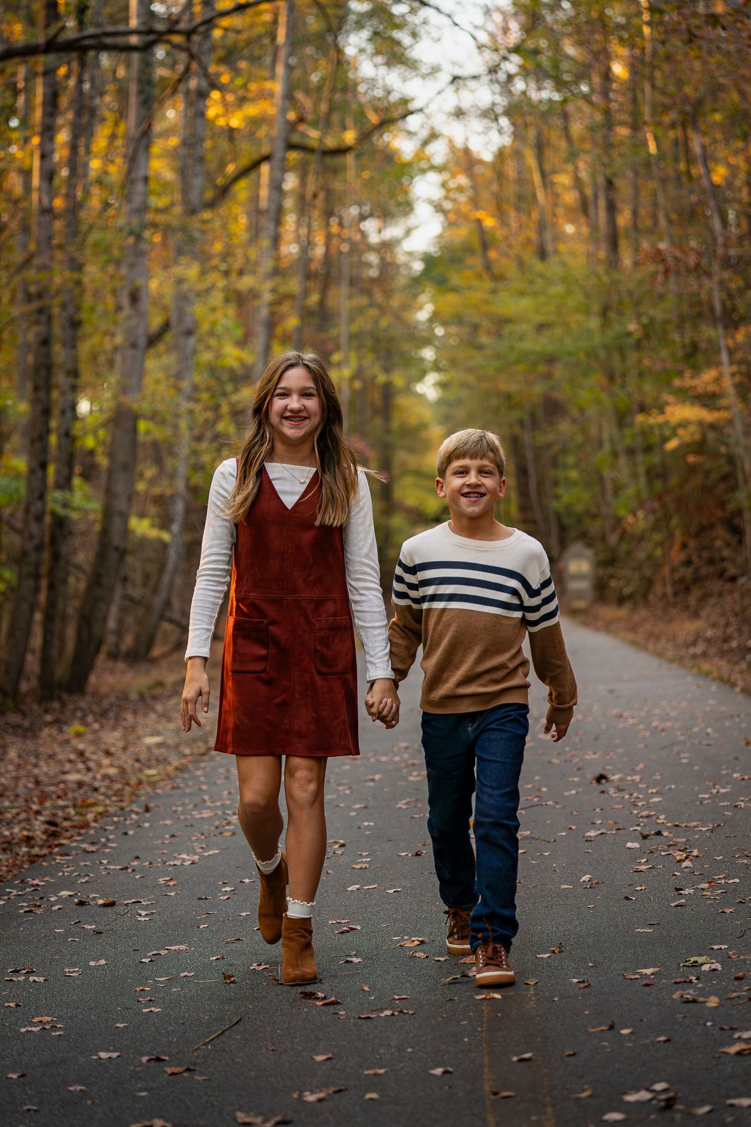 Children walking together on an autumn path surrounded by golden fall foliage.