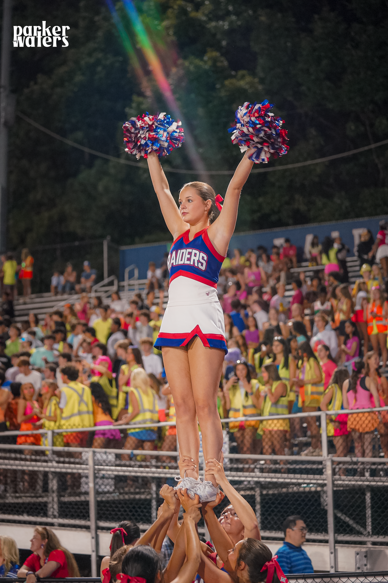 Cheerleaders perform a high-flying stunt routine in front of a crowded stadium.