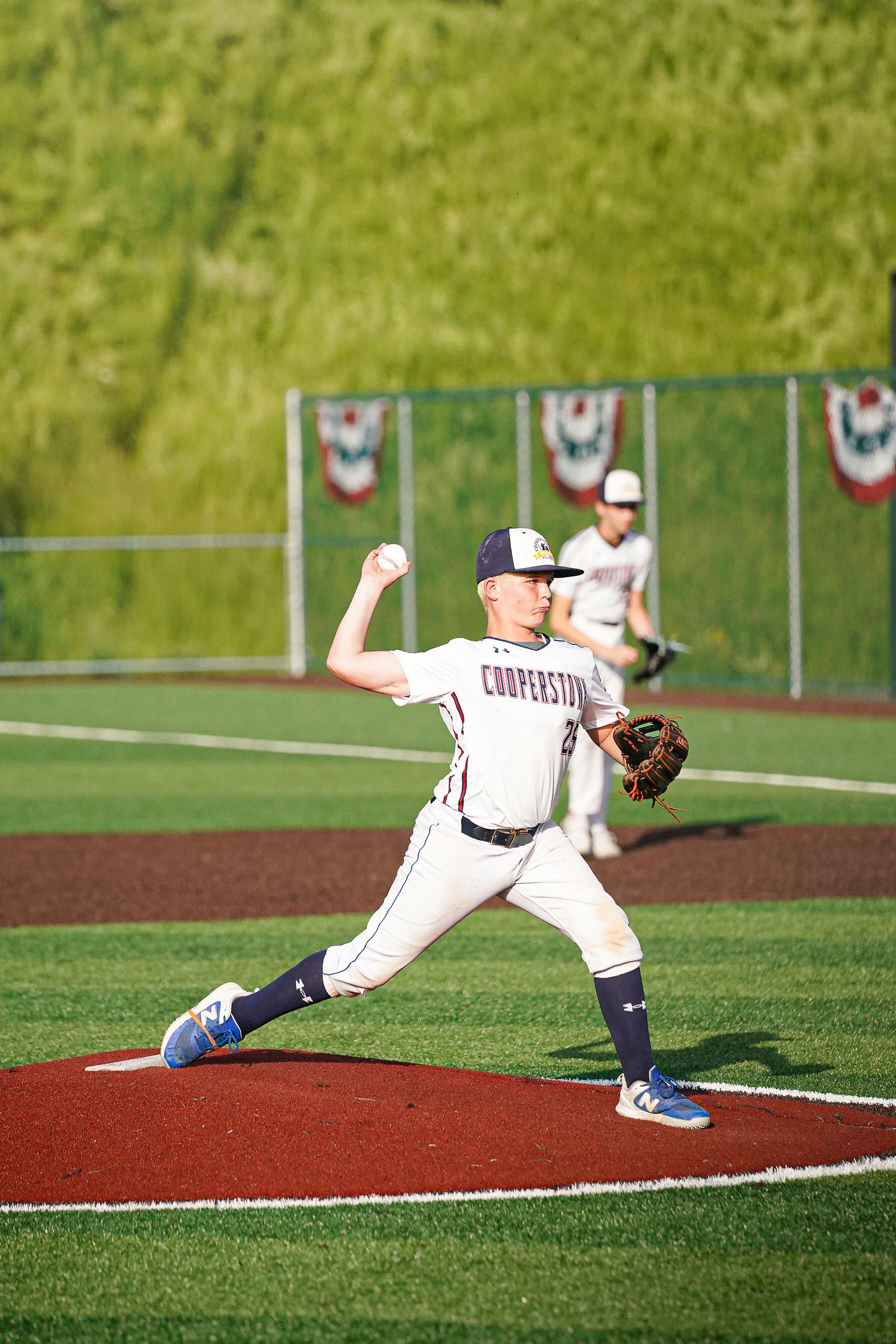 Baseball player demonstrating sliding technique on red clay field.