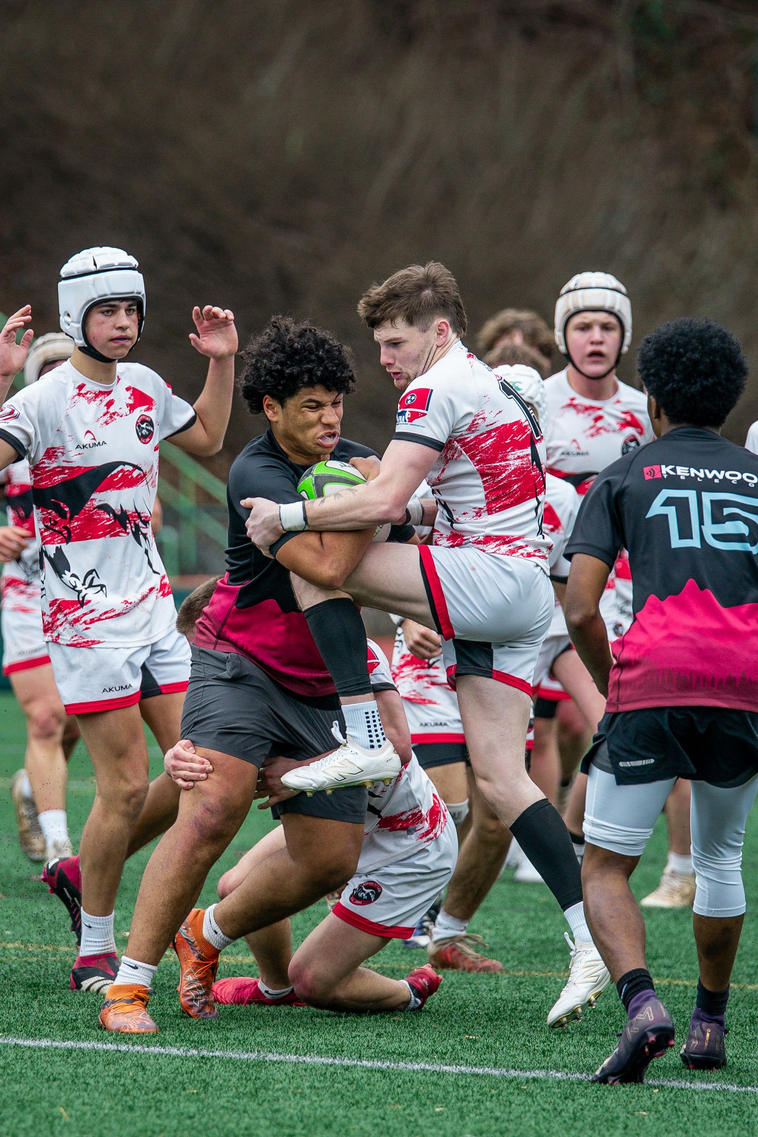 Rugby players engage in a scrum formation during an intense match on a grass field.