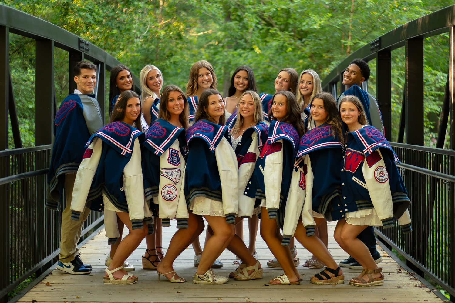 Group photo of students standing together on wooden bridge in casual attire.