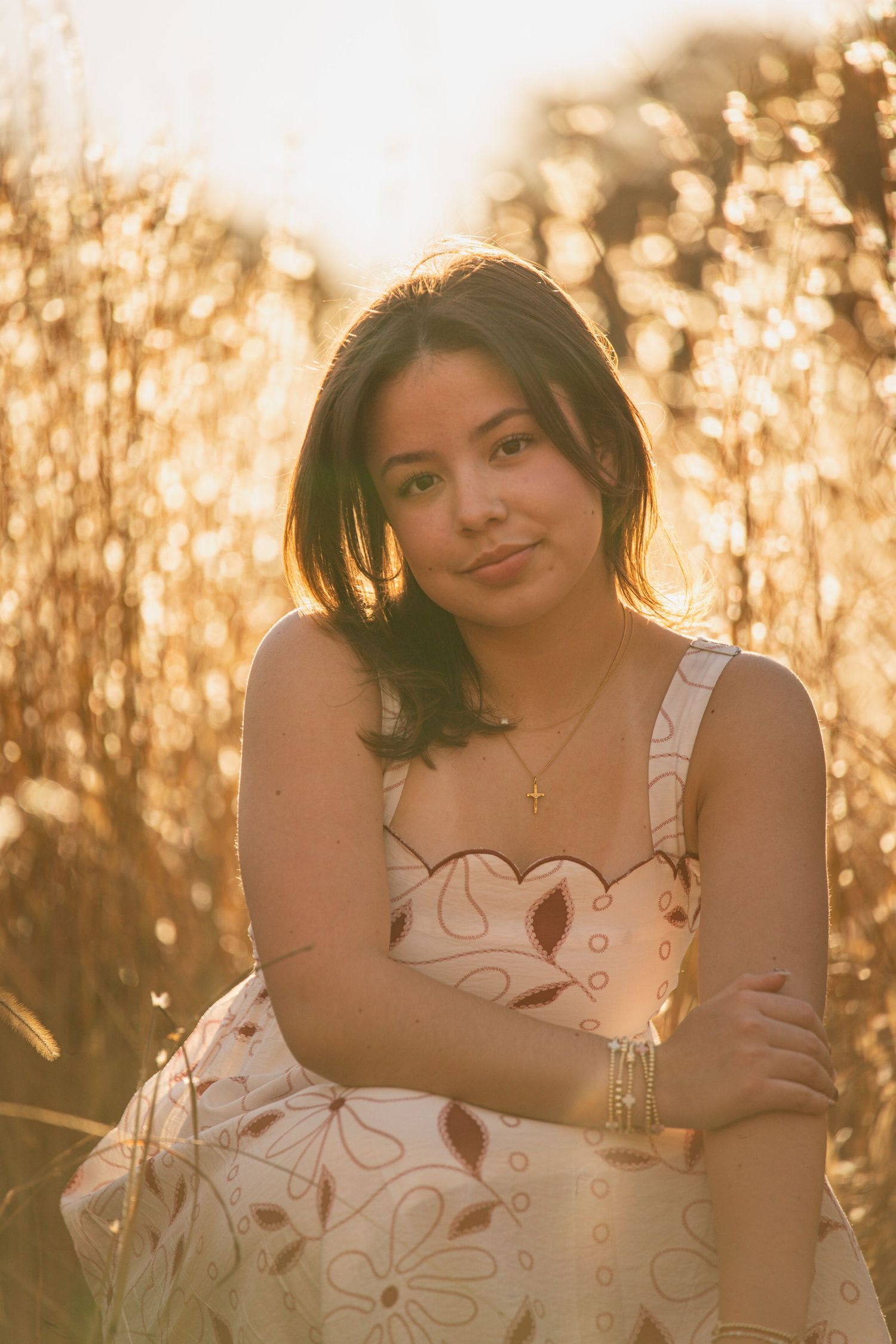 A person in a white dress poses outdoors during golden hour with warm sunlight creating a dreamy atmosphere.