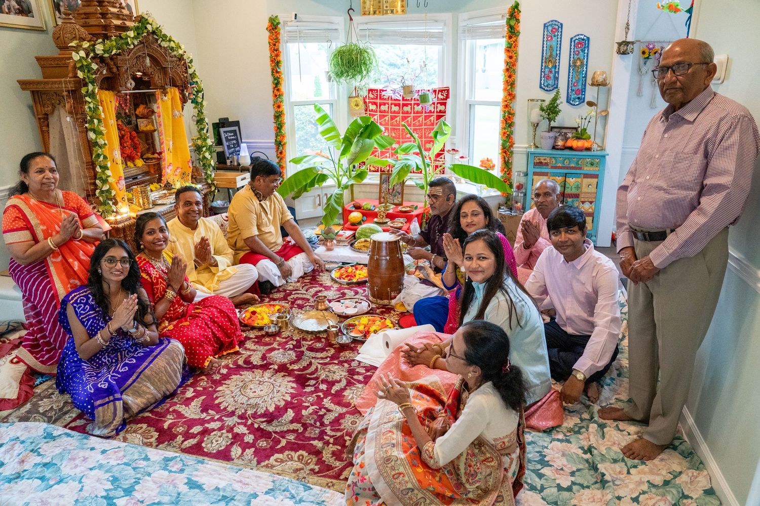 Indian family gathered for a traditional Hindu puja ceremony at home, wearing colorful traditional attire.