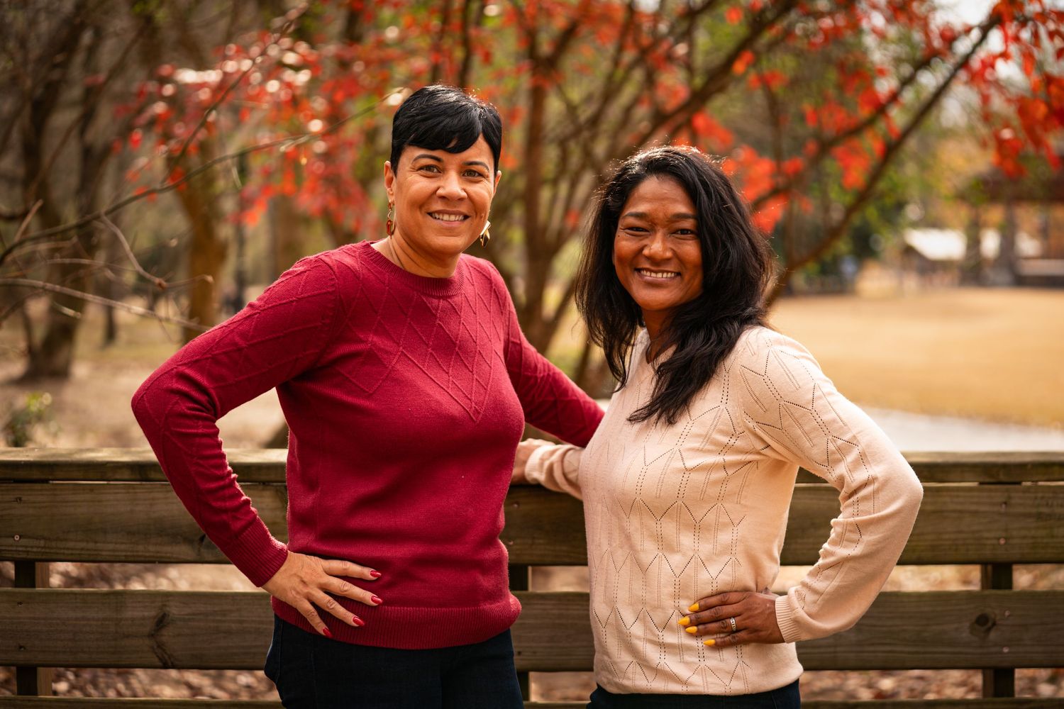 A couple in red and pink sweaters share joyful moments during an autumn outdoor photoshoot.