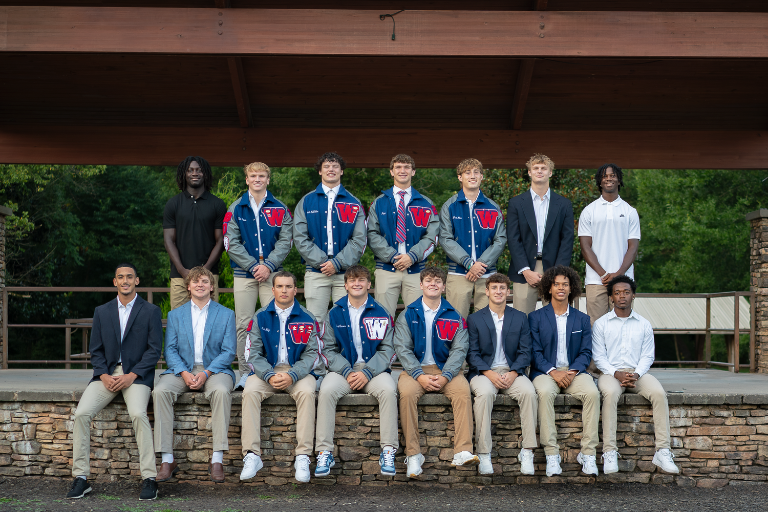 Large group portrait of people sitting on stone wall in coordinated blue and white outfits.