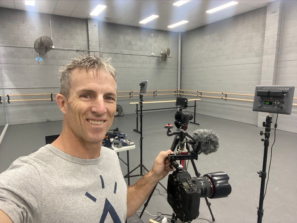 Professional video production setup in a bright studio with lighting equipment and camera gear.