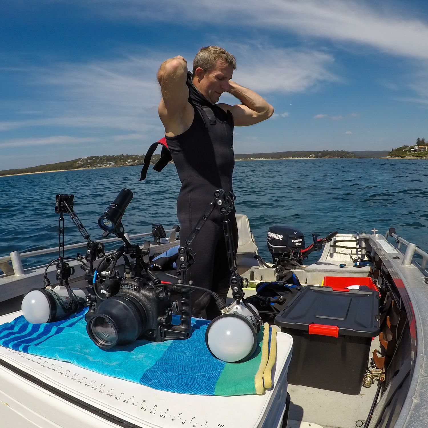 Diving equipment and gear laid out on a boat deck against a blue ocean backdrop.