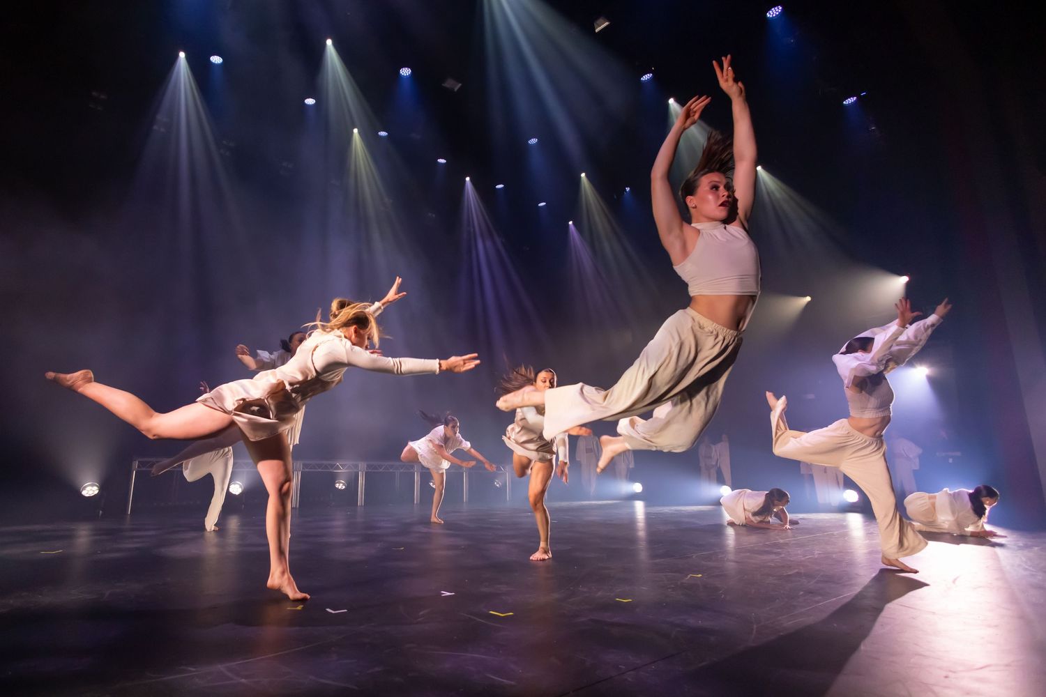 Modern dance performance with graceful movements under blue stage lighting.