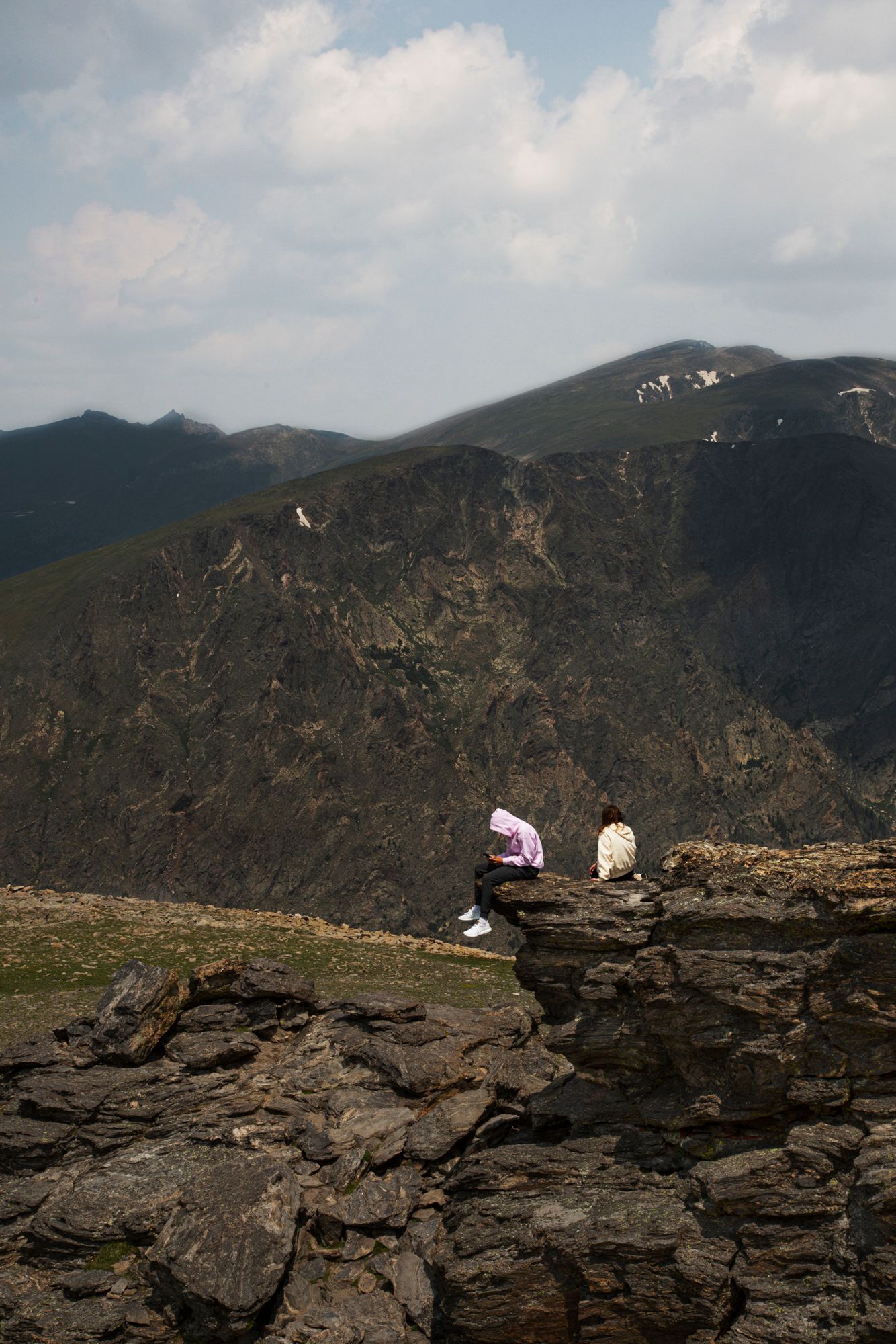 A panoramic sequence of rocky mountain terrain with distant peaks and cloudy skies in the background.