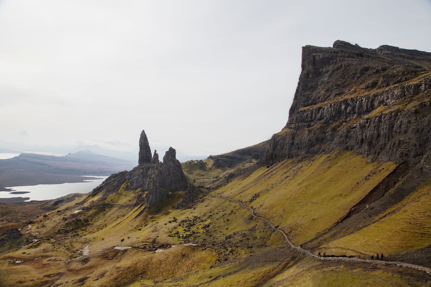 Dramatic rocky cliffs and green slopes of the Quiraing on Isle of Skye in Scotland under moody skies.