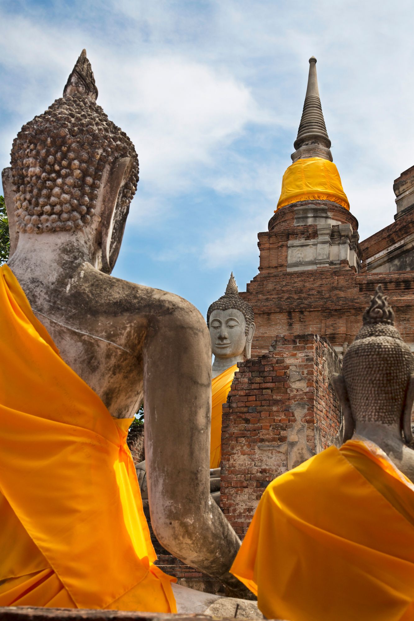 Ancient Buddha statues draped in orange robes at Ayutthaya Historical Park in Thailand.
