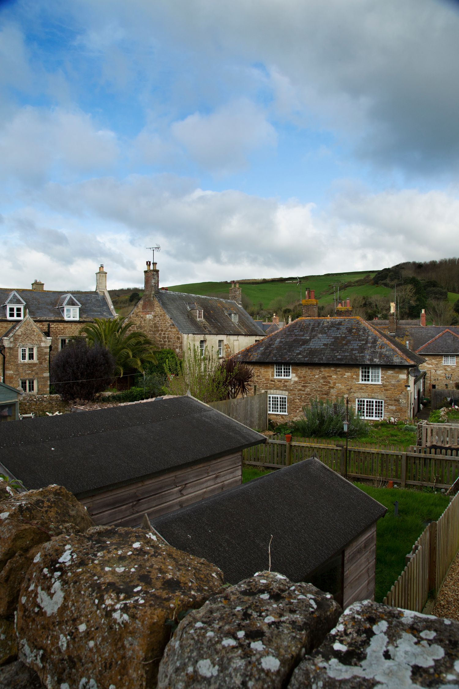 Traditional stone cottages with slate roofs nestled on a hillside in a British village.