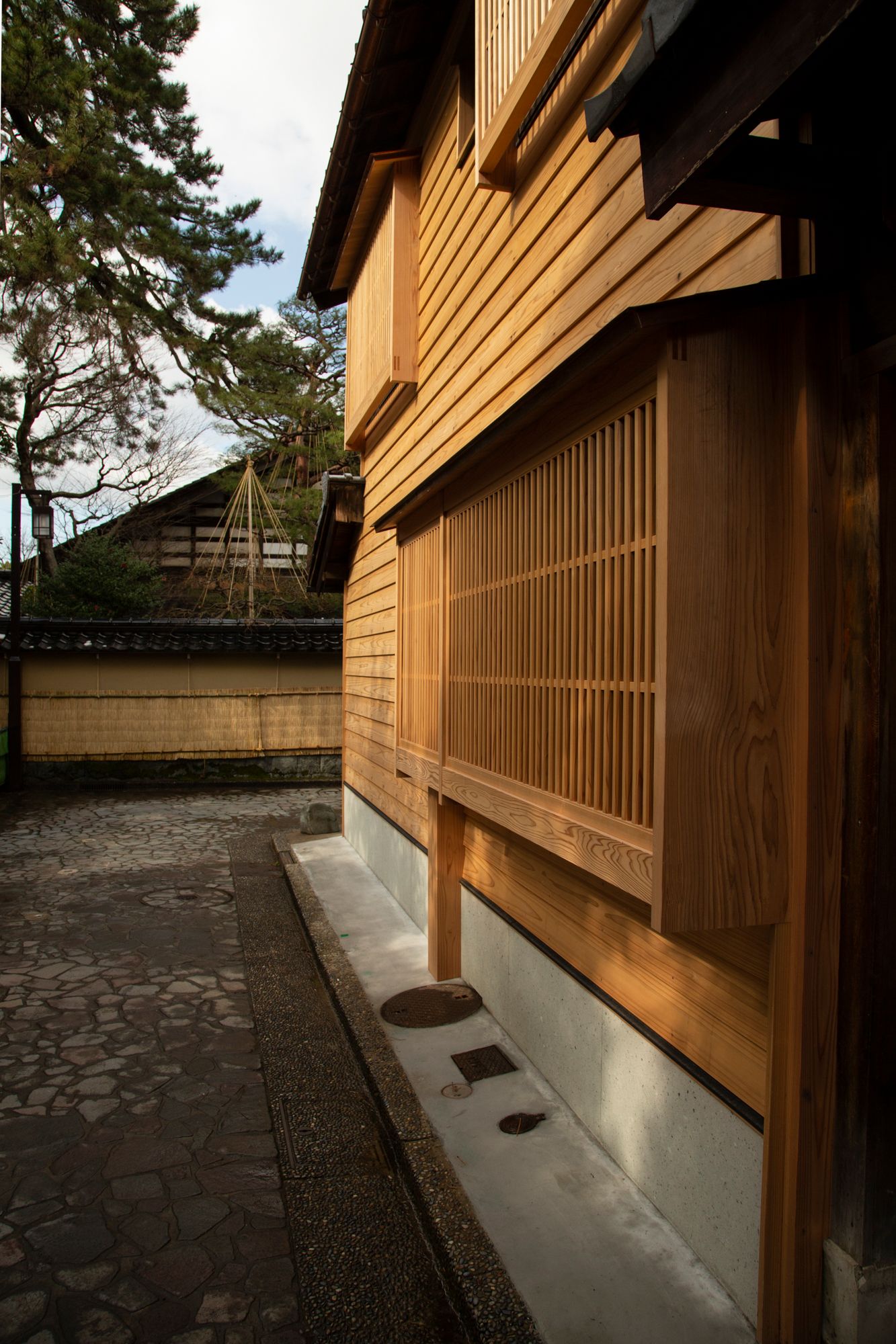 Traditional Japanese wooden architecture with vertical slats and stone pathway.