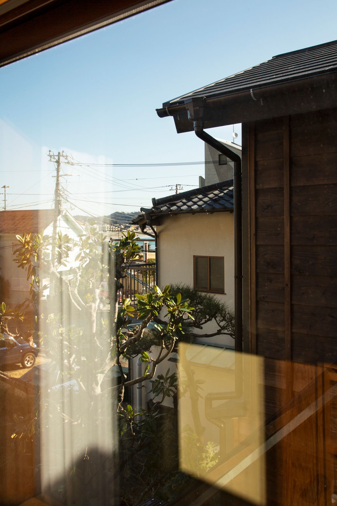 Sunlight casts shadows on traditional Japanese wooden house exterior.