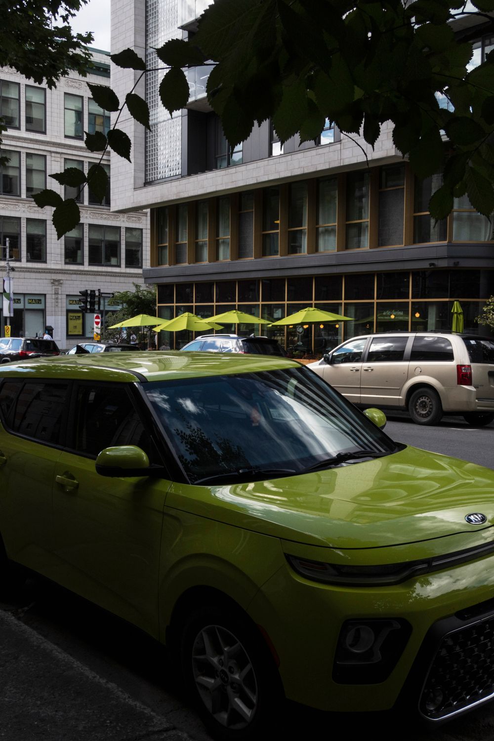Lime green Kia Soul electric vehicles parked in front of a modern building.