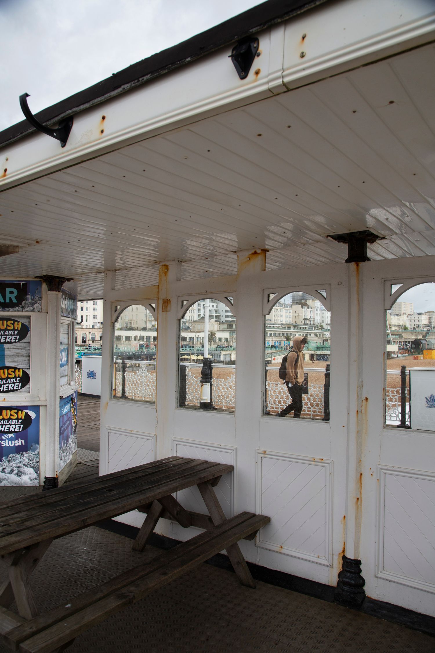 Rustic pier shelter interior with wooden bench and arched windows overlooking the sea.