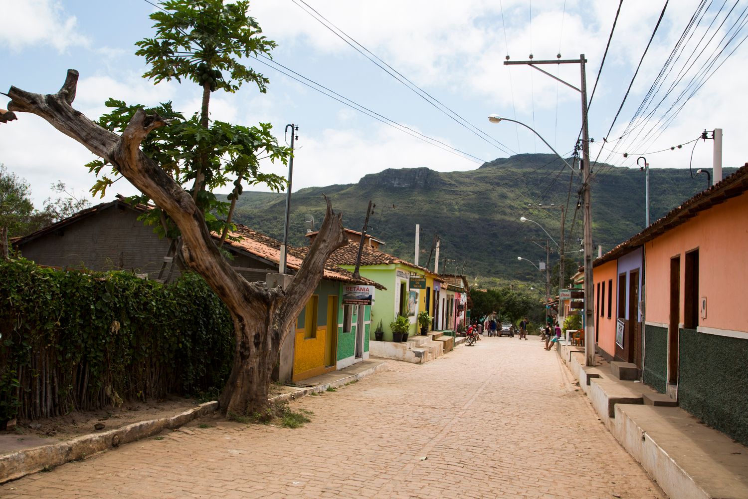 Quiet residential street with colorful houses and mountain views in the distance.