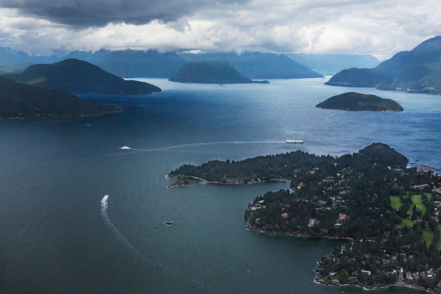 Panoramic view of mountainous coastline with islands dotting the calm waters of Vancouver harbor.