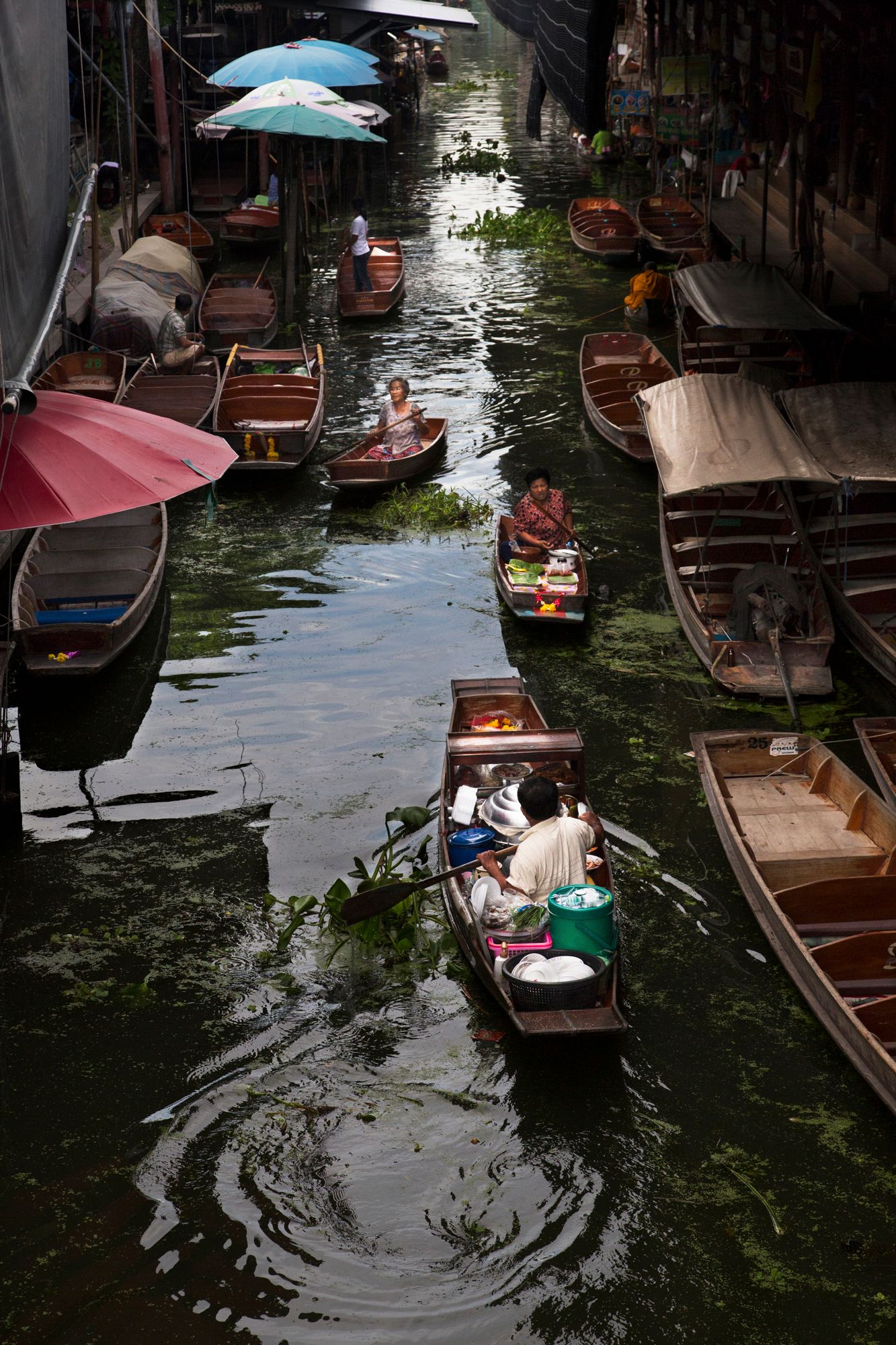 Traditional wooden boats floating in a dark canal with rippling water.