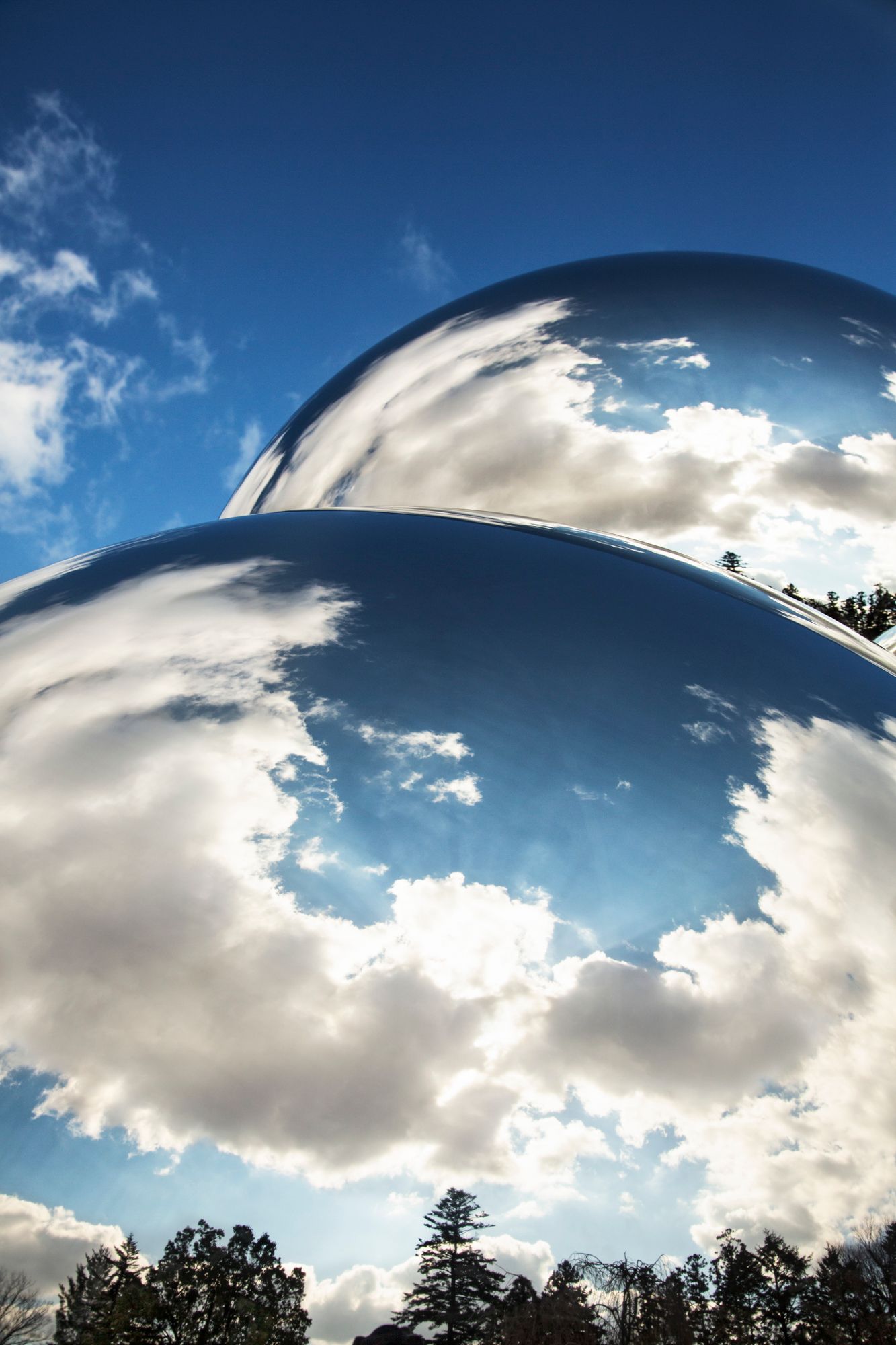 Dramatic wide-angle shot of white puffy clouds against a deep blue sky.