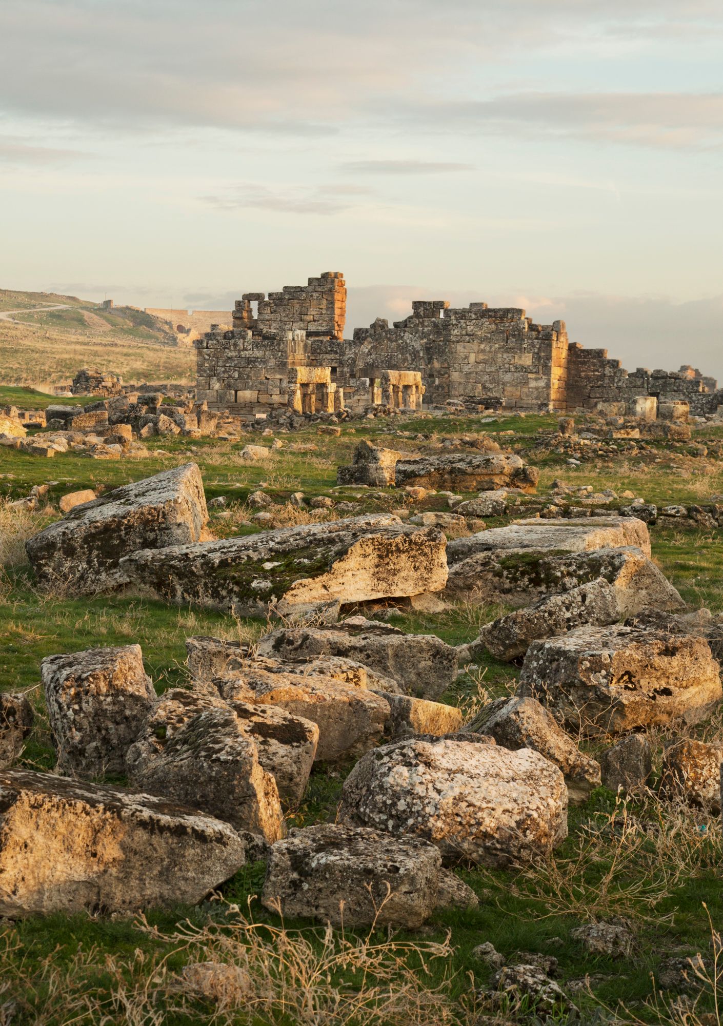 Ancient stone ruins of historic city on hillside during golden hour.