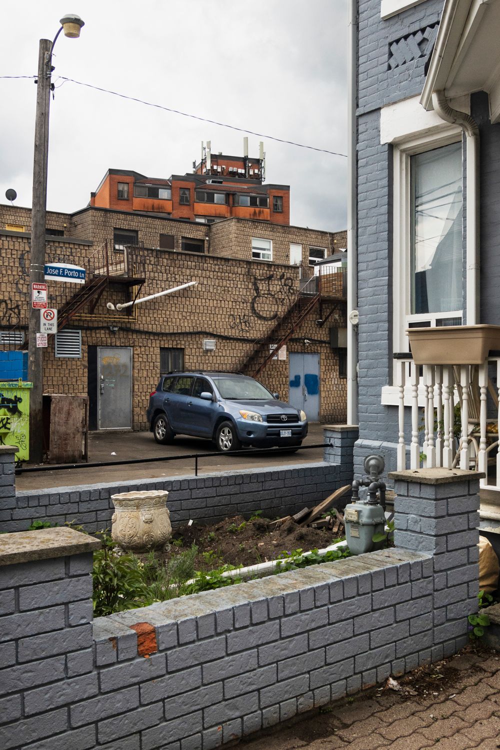 Grey painted brick wall with parked cars visible in the background.