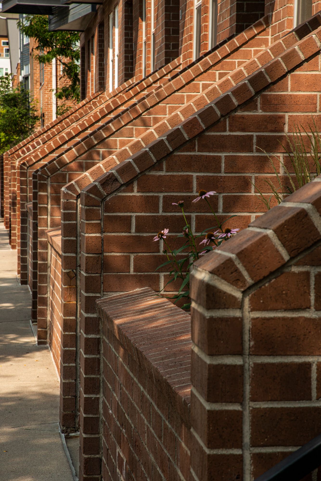 Architectural detail of a brick building exterior showing diagonal steps and shadow patterns on a sunny day.