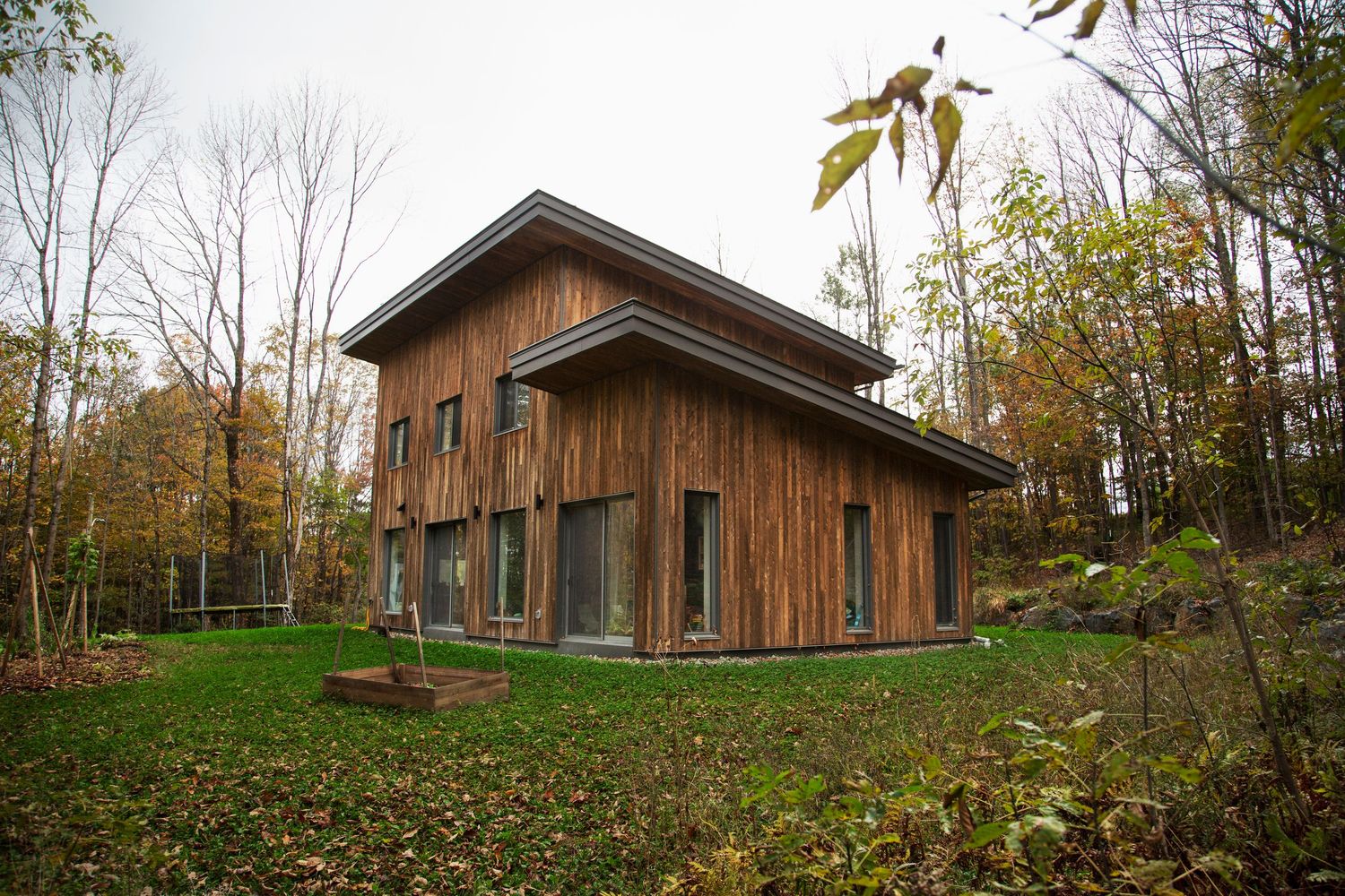 Contemporary wood-clad building with horizontal siding extends along a grassy hillside.