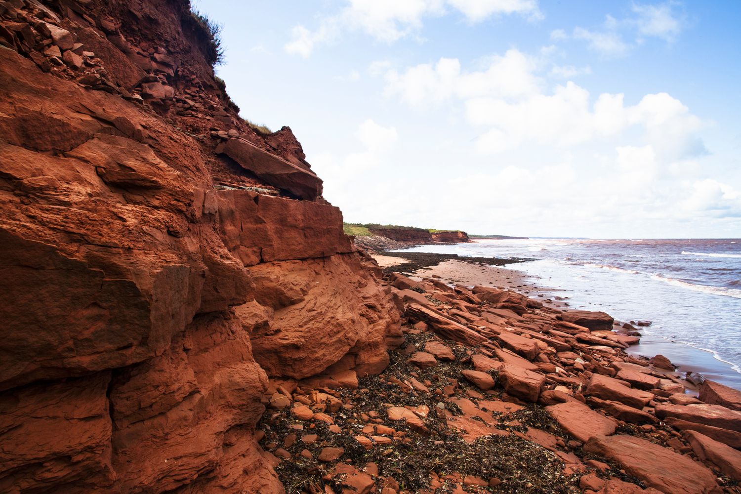 Red sandstone cliffs and rock formations stretch along a scenic coastal landscape.