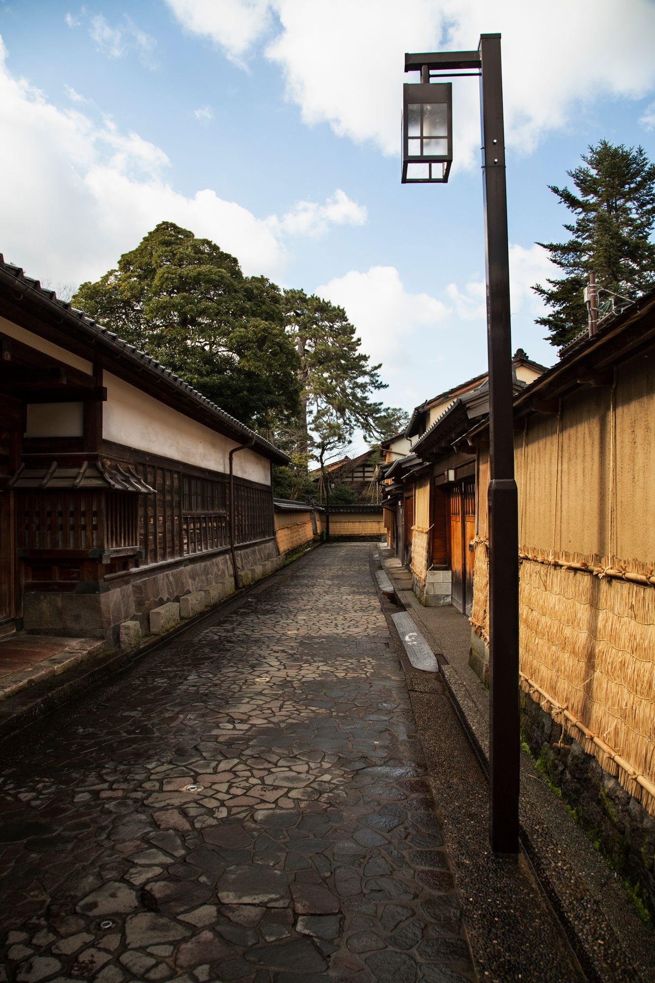 Stone-paved pathway lined with traditional Japanese buildings and lanterns.