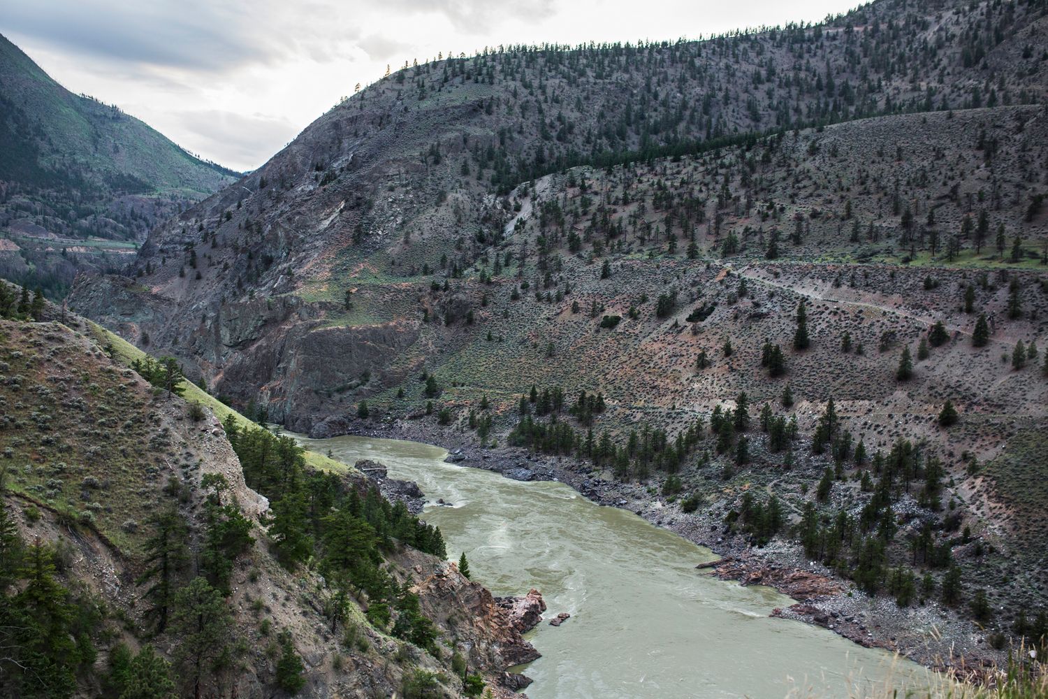 Fraser River cutting through steep mountain canyon with turquoise waters and rugged terrain.