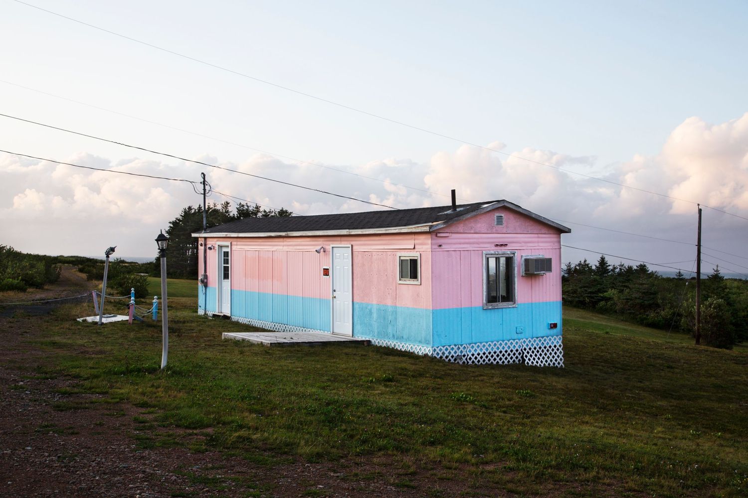 Pink and blue mobile homes scattered across rural hillside at sunset.