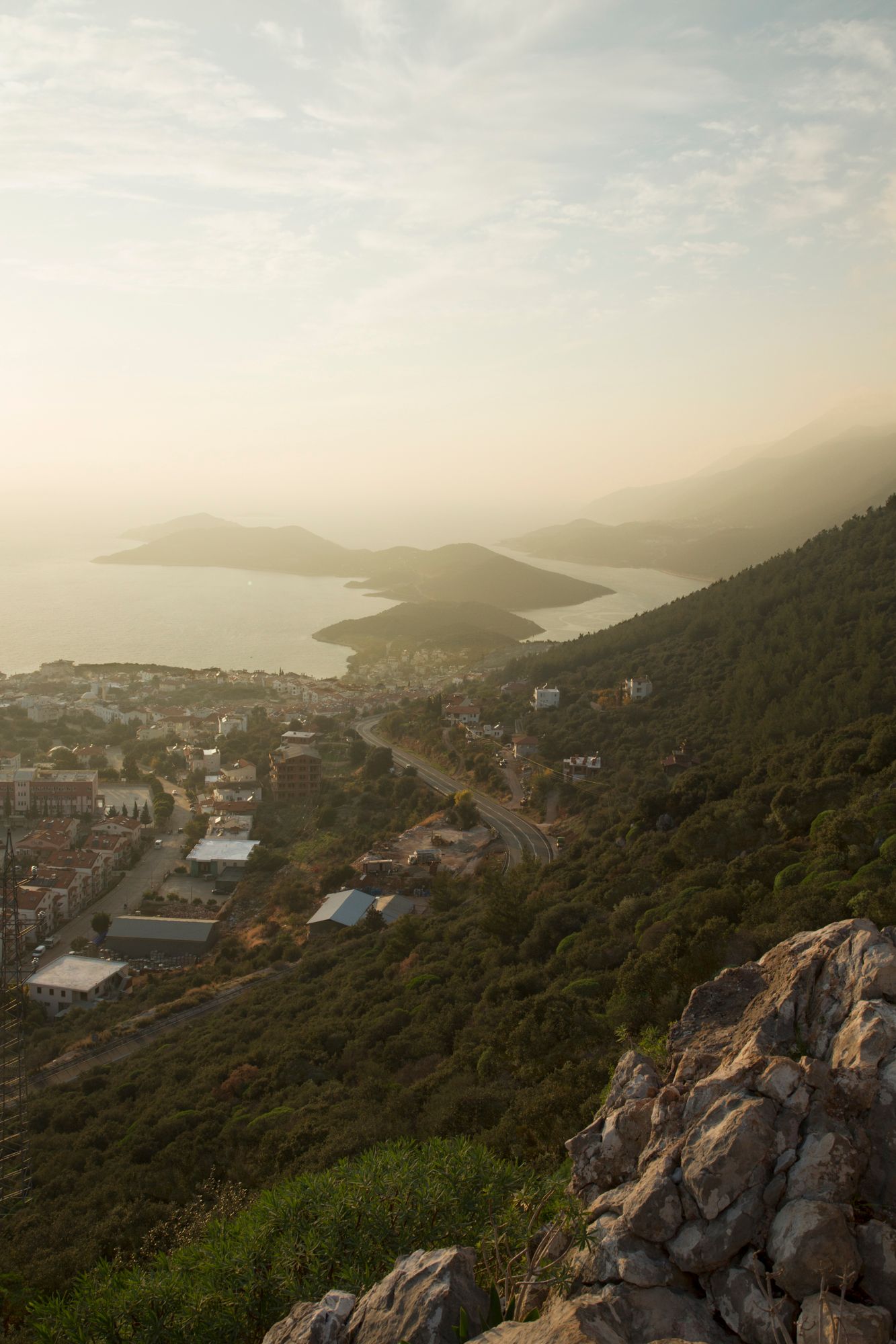 Sunset panorama of hillside Mediterranean town with islands visible in distant waters.