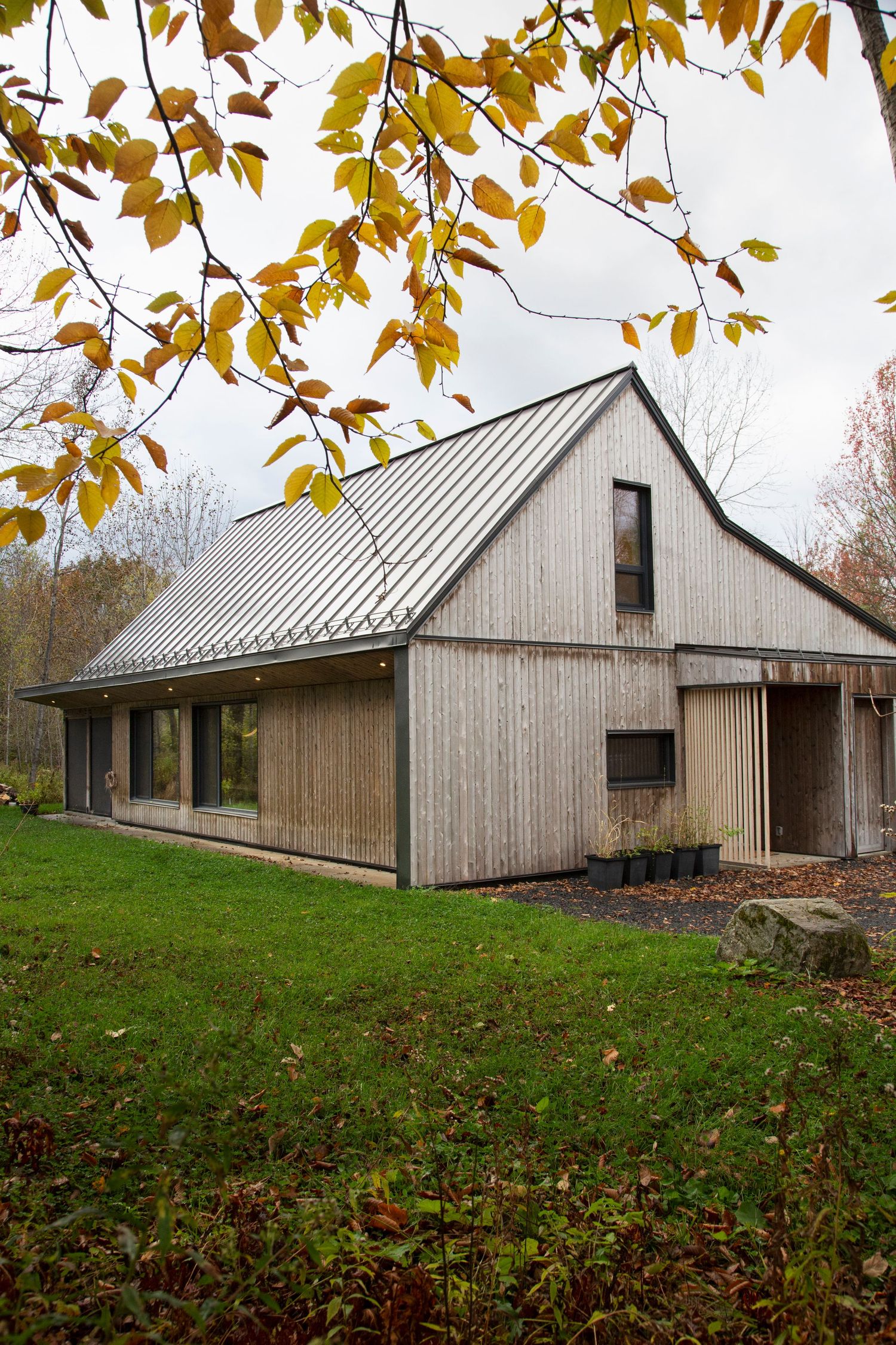 Long wooden barn-style building with metal roof nestled in fall foliage.