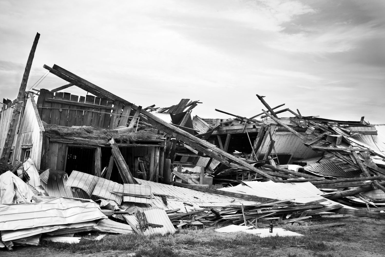 Black and white photograph showing severe storm damage to buildings with collapsed roofs and scattered debris.