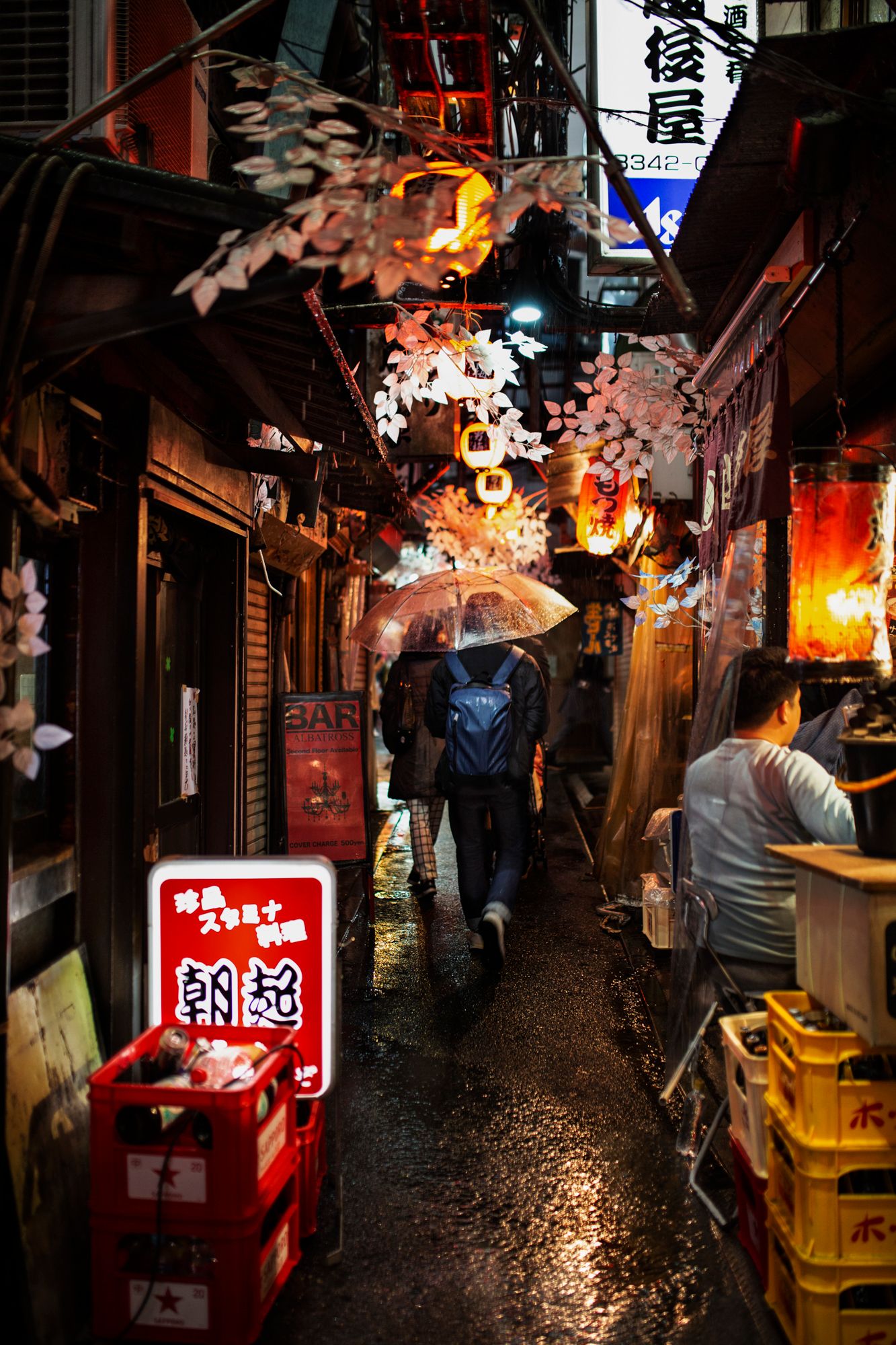 Narrow alley in Japan with glowing red lanterns and decorative elements overhead.