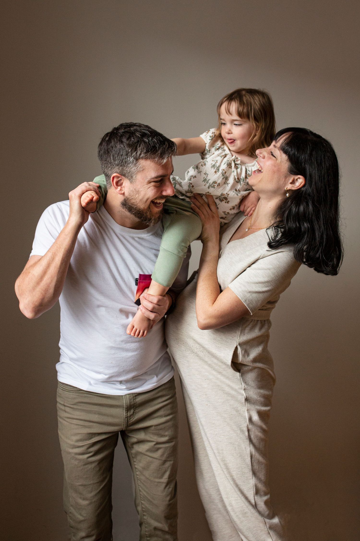 Two people playfully drinking water from bottles against a neutral background.