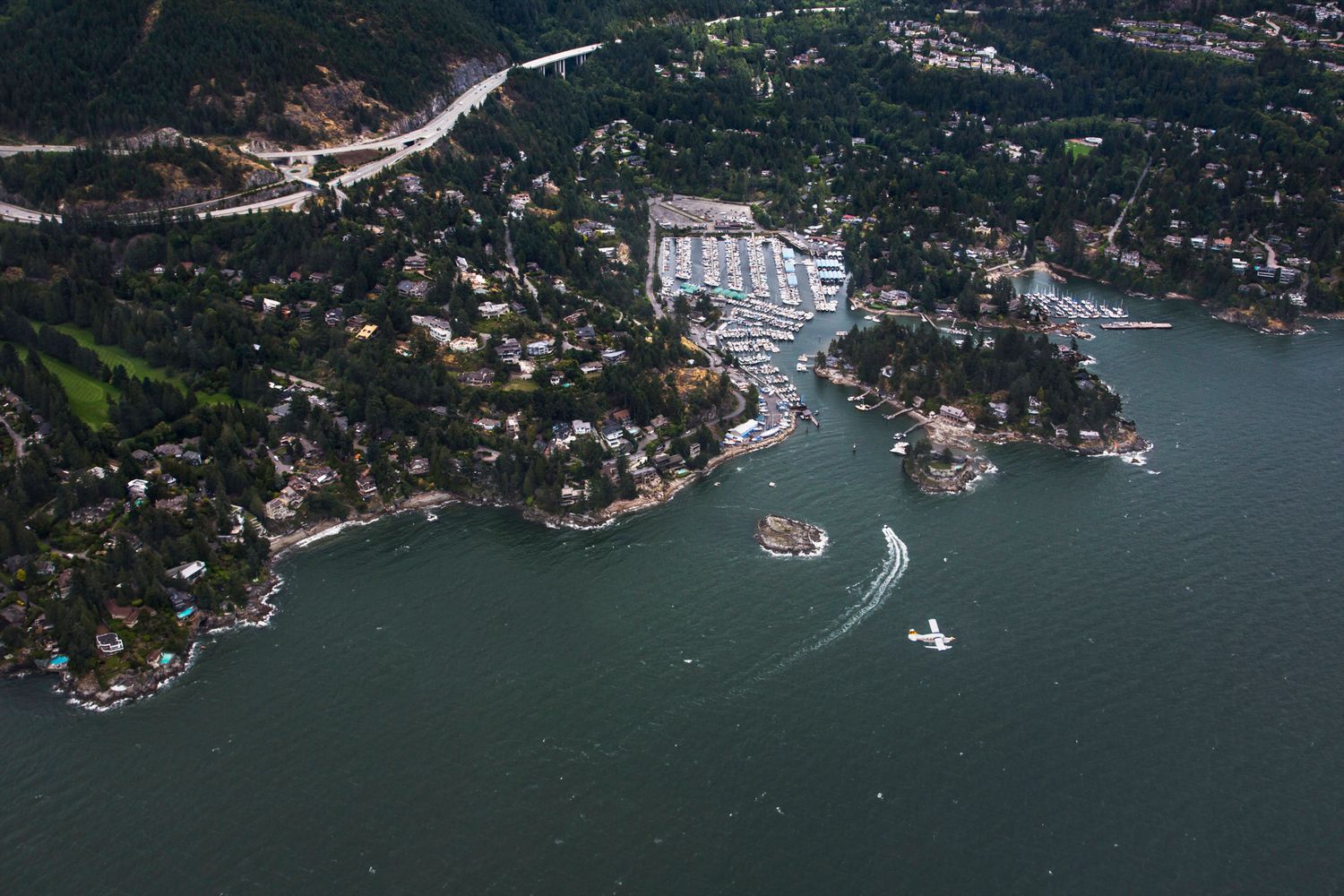 Bird's eye view of Vancouver's coastal residential areas and marinas nestled between mountains and sea.