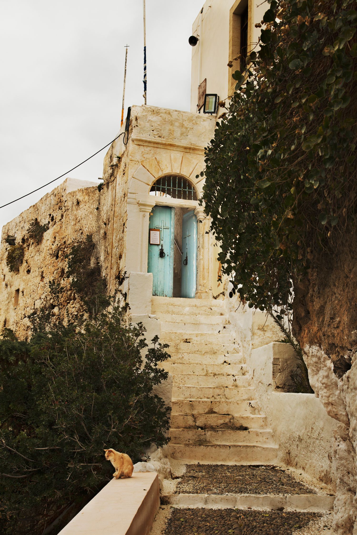 Stone stairway with blue door and cream colored walls in Mediterranean architecture.