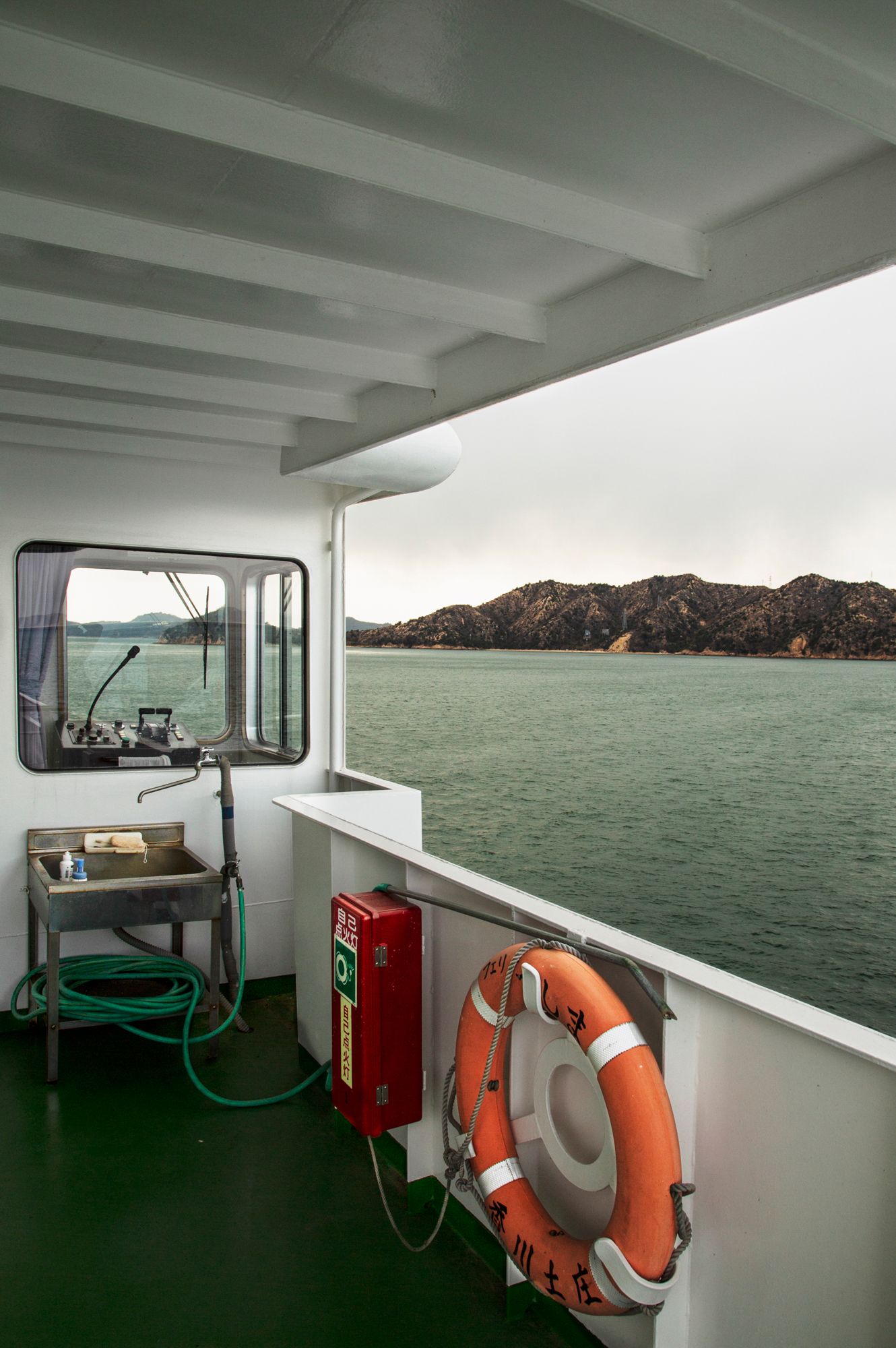 View from a boat deck showing life preservers and safety equipment with misty waters beyond.