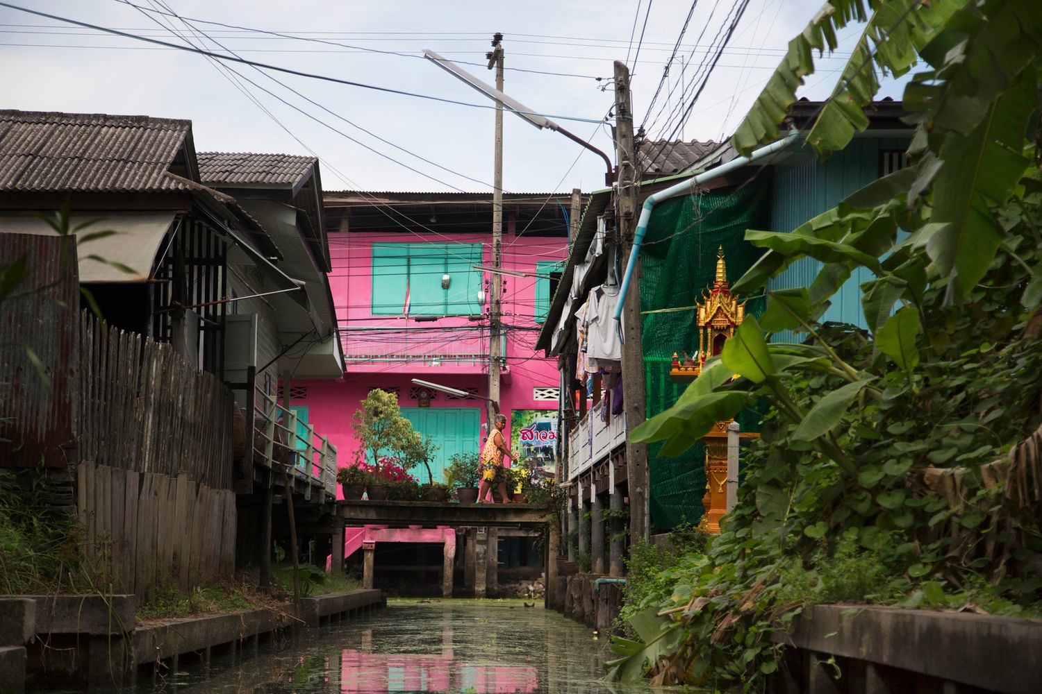 Rural village houses with power lines and pink walls along a narrow path.