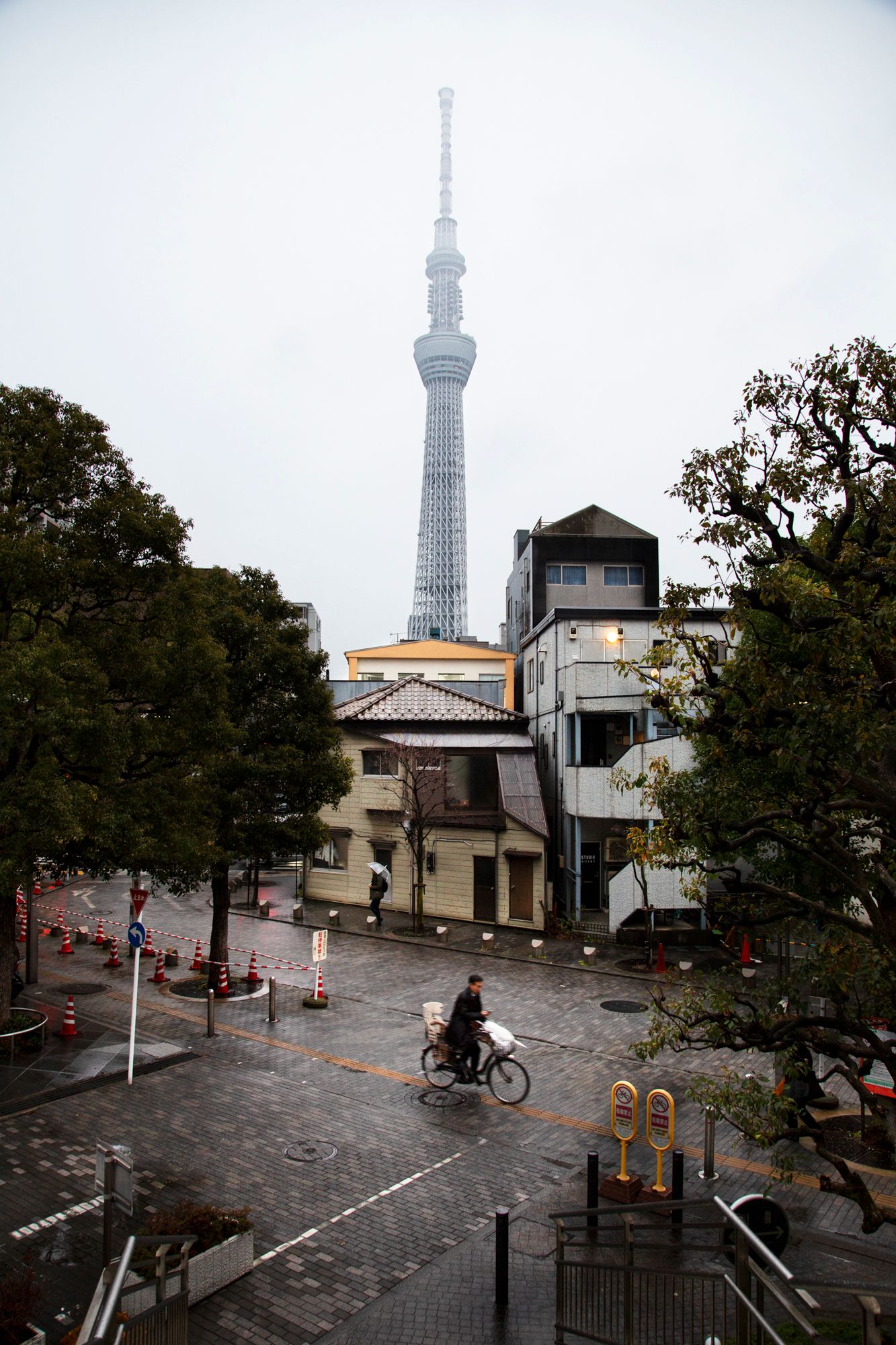 Tokyo Skytree tower visible in distance through cloudy urban landscape.