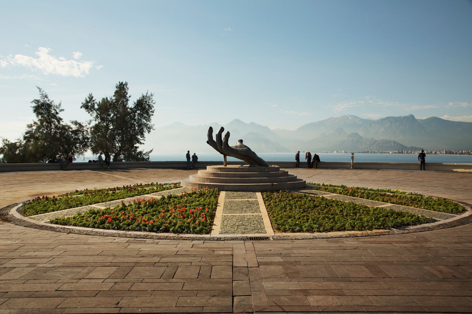 Modern circular plaza with mountain views and decorative landscaping in coastal setting.