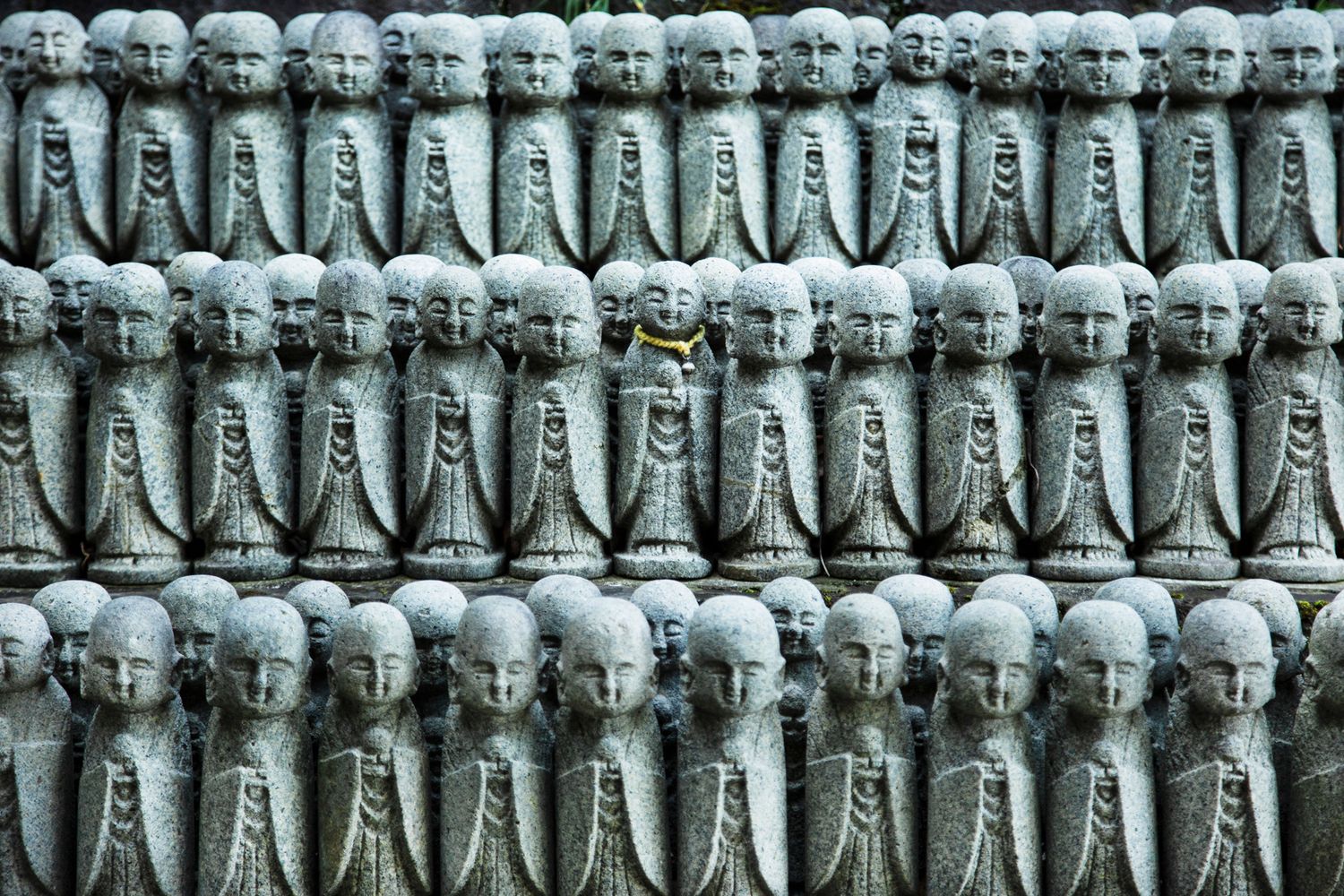 Rows of identical stone Jizo statues at a Japanese temple.