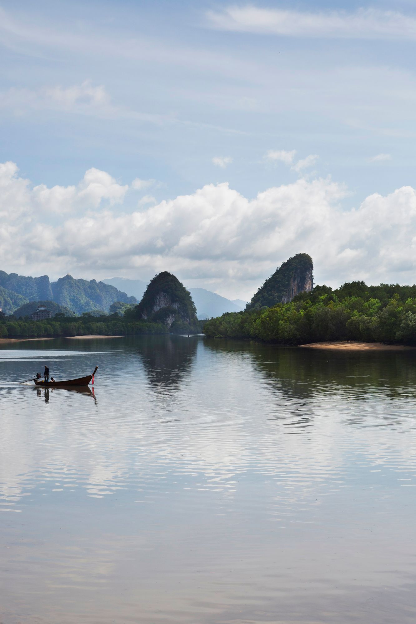 Tranquil seascape with limestone karsts and small fishing boats dotting the calm waters.
