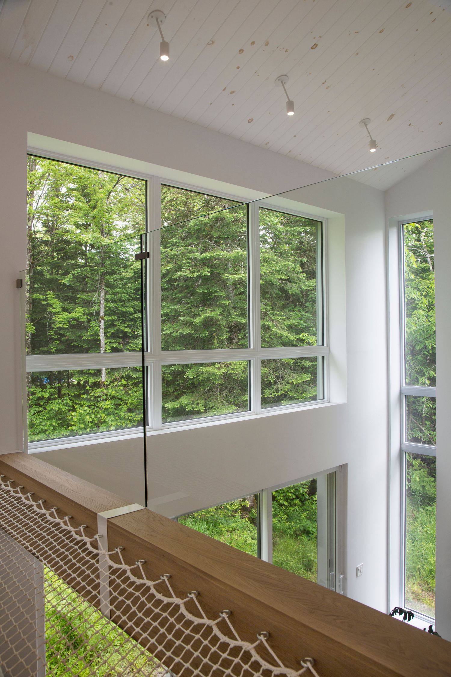White interior space with large windows overlooking lush greenery and decorative lattice railings.