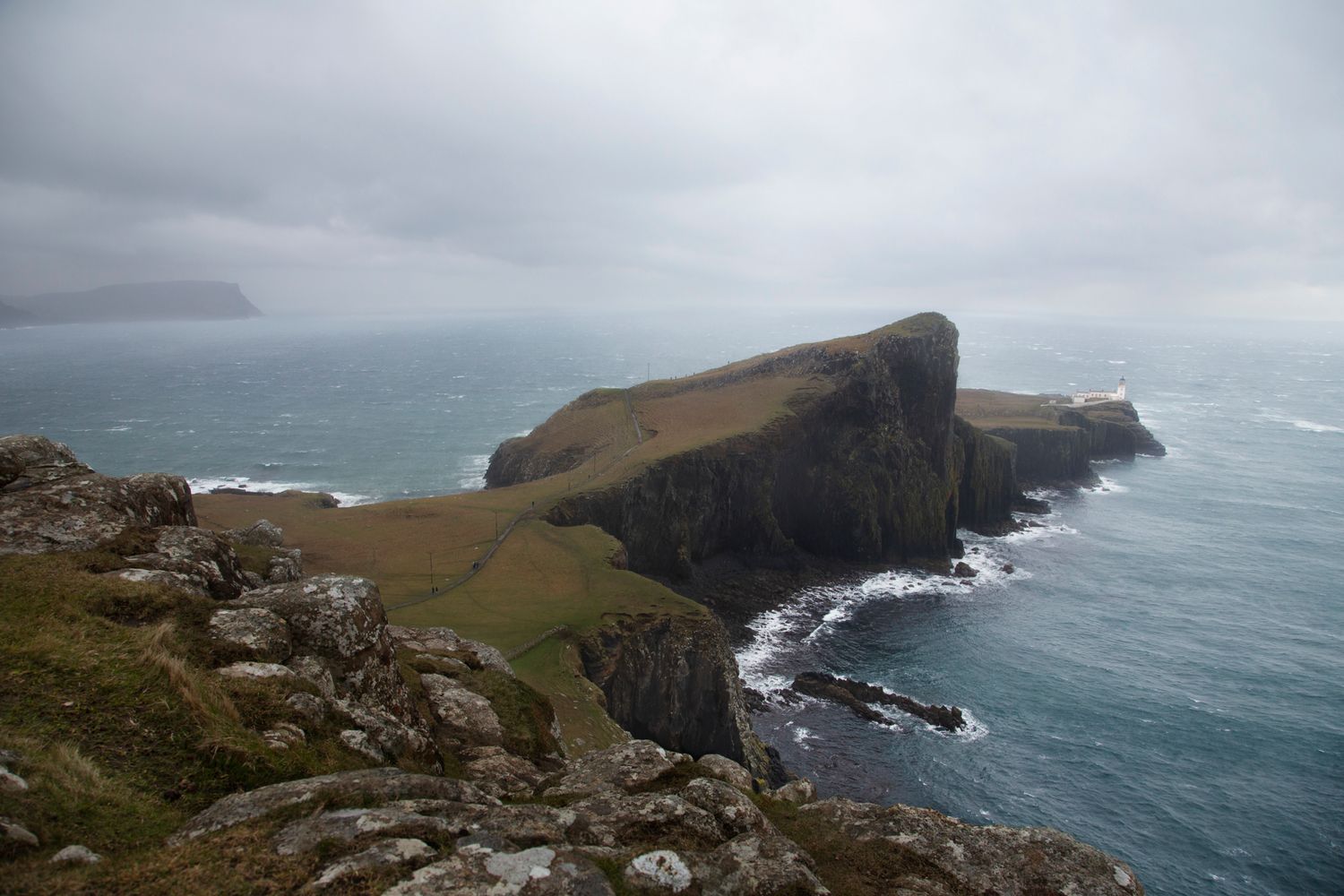 Dramatic coastal cliffs rise above the misty ocean along Ireland's rugged western shoreline.