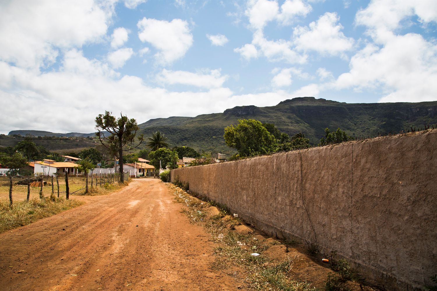 Dirt path along stone wall winding through Mediterranean coastal landscape.