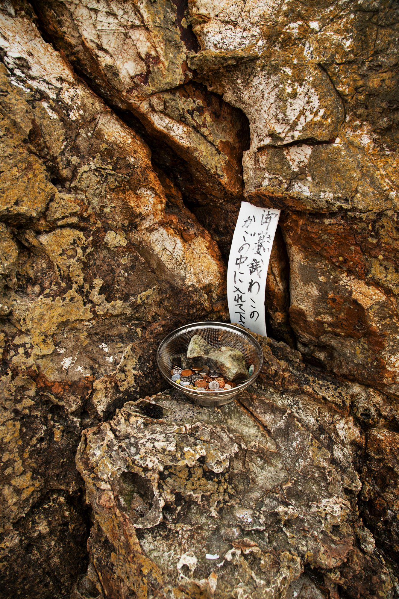 Small objects and notes tucked into crevices of a weathered rock wall texture.